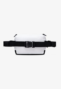 Marsupio bianco in tessuto con cinturini e dettagli neri, dotato di una fibbia centrale e scomparti con zip. Texture liscia, forma rettangolare.
