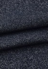 Tessuto a maglia blu scuro con un motivo testurizzato, caratterizzato da accenti di filo argentato intrecciati. Superficie morbida e leggermente pelosa.