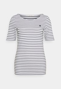 Camiseta blanca con rayas horizontales negras, cuello redondo, mangas cortas y un pequeño logo bordado en el lado izquierdo del pecho. Textura suave.
