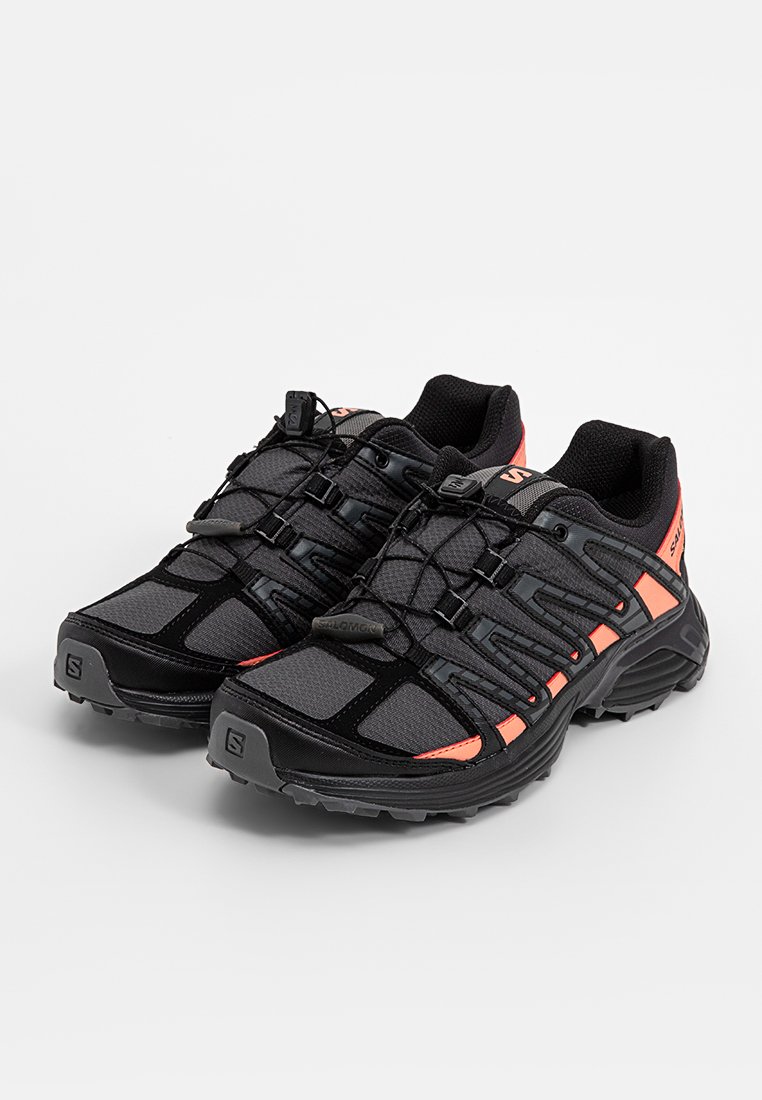 Baskets de sport noires et orange avec un dessus en maille texturée, une semelle robuste et un système de laçage rapide pour un maintien sécurisé.
