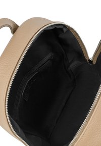 Beige leren tas met een gestructureerd oppervlak, ritssluiting aan de bovenkant en een zwarte stoffen binnenkant met een klein ritsvakje.