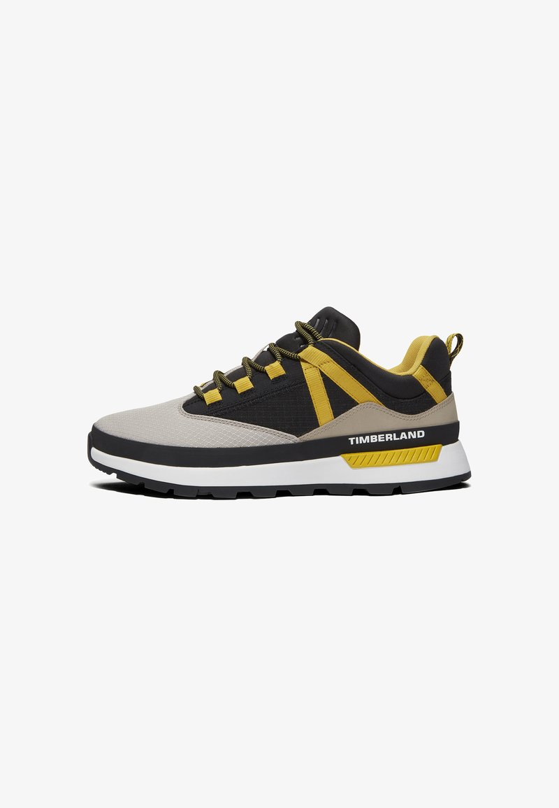 Grijze en zwarte sneaker met gele accenten. Heeft een bovenwerk van mesh, een gevoerde zool en een karakteristieke "TIMBERLAND" branding aan de zijkant.