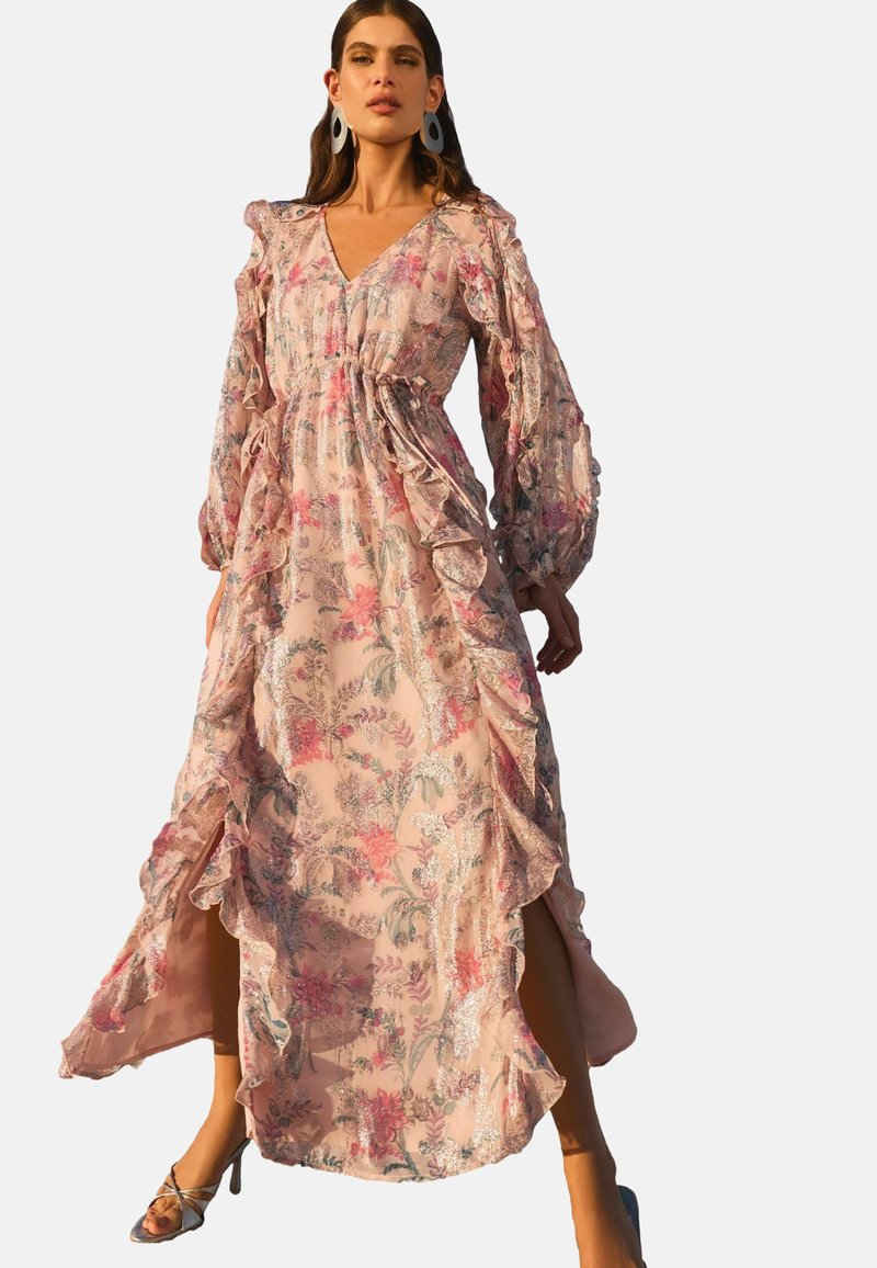 Kwiatowa maxi sukienka z miękkiego różowego materiału z falbanami przy rękawach, głębokim dekoltem w serek i bokami z rozcięciami; posiada związany pas i roślinny nadruk.