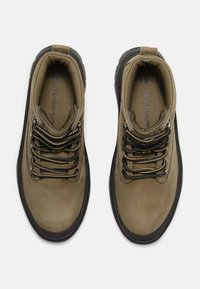 Brown hiking shoes with a smooth, textured leather upper, rounded toe, and black rubber outsole. Features metal eyelets and patterned laces.
