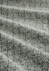 Gray textured fabric with a patterned weave, featuring light and dark threads that create a subtle, layered effect and a soft surface.