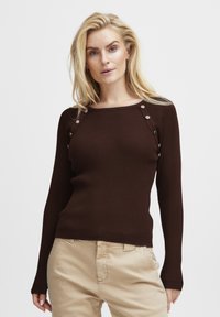 Maglione lungo a maniche lunghe color marrone a costine con scollatura quadrata, caratterizzato da dettagli metallici a pressione sulle spalle e polsini aderenti.