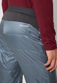 Isolerade byxor i grått med quiltad struktur. Har en svart elastisk midja och en vit logga på baksidan.