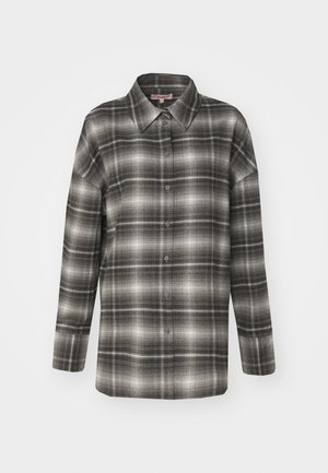 Cămașă din flanel în carouri alb-negru, cu guler ascuțit, mâneci lungi și închidere cu butoane, având o textură ușor șerpuie.