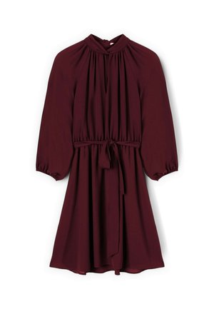 Robe bordeaux en tissu fluide avec de longues manches bouffantes, un col montant et une taille à nouer, ornée de doux plis tout au long.
