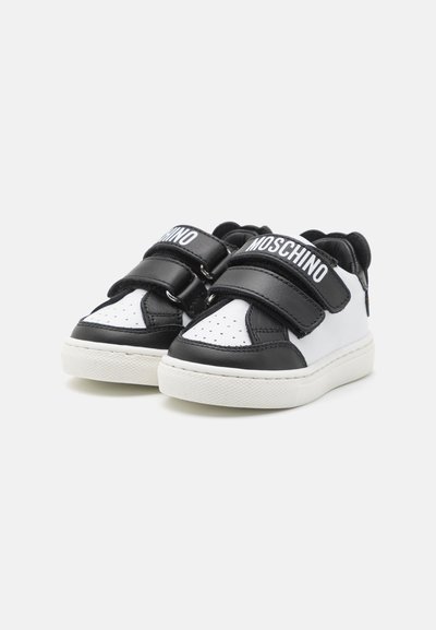 Sneaker in bianco e nero con tomaia in pelle liscia, punta perforata, due larghe cinghie in Velcro e suola in gomma bianca texturizzata.