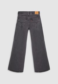 Jean noir à jambes larges avec deux poches arrière, passants de ceinture et un patch en cuir marron sur la ceinture, posé à plat sur fond blanc.
