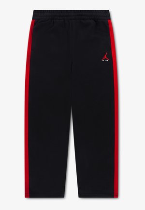 Pantalon de survêtement noir avec bandes latérales rouges, taille élastique et petit logo Jumpman Air rouge sur la cuisse gauche.