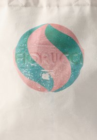 Lerretsbæreveske med et sirkulært design i rosa og teal, med en teksturert finish og falmede grafiske detaljer.