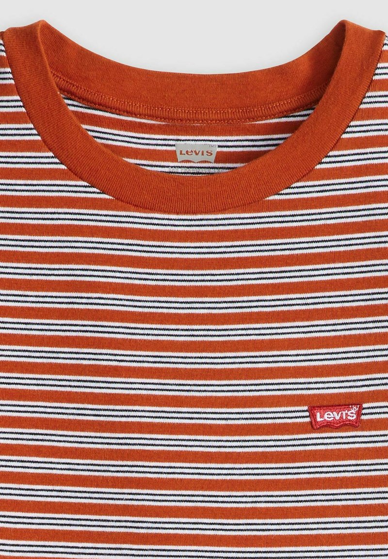 Camiseta a rayas con un patrón en naranja, negro y blanco, con un cuello redondo y una etiqueta del logo de Levi's en rojo en la parte inferior izquierda.