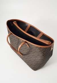 Barna mintás vászontáska világosbarna bőr díszítéssel. Két fogantyúval, belső cipzáras zsebbel és fekete textil béléssel rendelkezik.