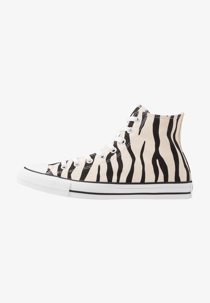 Höga sneakers med ett överdel av svart och vitt zebra-mönstrat kanvas, vit gummitå, snörning och en svartrandig sula.