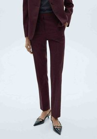 Burgundske hlače po meri s slim fit krojem, teksturirano tkanino in subtilnim črtastim vzorcem. Usklajene z črnimi čevlji s pointed-toe.