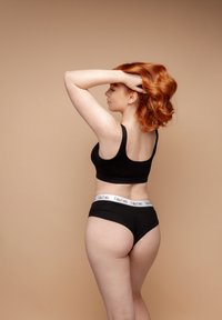 Black cotton crop top and matching high-waisted underwear with a white logo band, showcased against a neutral background.