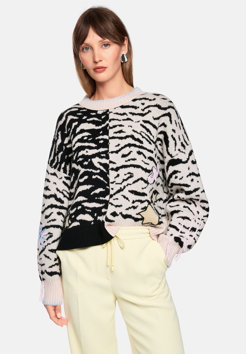 Gestrickter Pullover mit Farbblock-Design in Beige, Schwarz und Hellrosa, mit Tigerstreifen und dekorativen Applikationen, gerippten Bündchen und Ausschnitt.