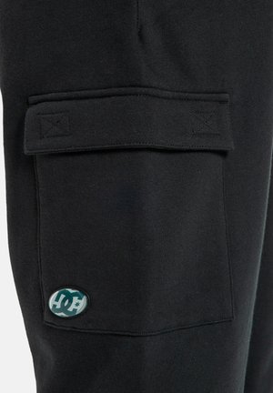 Zwarte cargobroek van zachte stof met een klepzak en een rond logopatch. Het ontwerp bevat gestikte details en heeft een relaxte pasvorm.