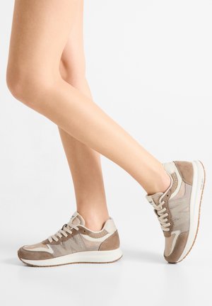 Zapatillas beige con materiales mixtos, incluyendo ante y malla; puntera redondeada, diseño con cordones y suelas acolchadas con acabado texturizado.