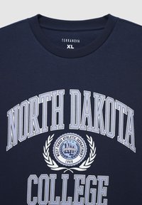 Felpa di cotone blu navy con scollatura rotonda. Presenta la scritta "NORTH DAKOTA COLLEGE" in grande carattere bianco e un emblema grafico centrale con alloro.