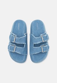 Blå denim slidesandaler med två justerbara silverfärgade spännen, fransiga kanter, platta sulor och texturerade innersulor för komfort.