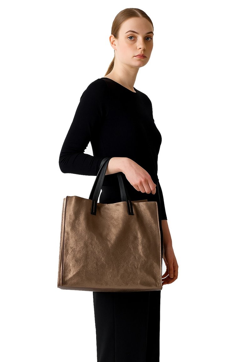 Borsa tote marrone strutturata con manici neri, caratterizzata da una forma rettangolare ampia e hardware minimal, tenuta da una persona con un top nero.