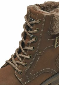 Bottine en cuir marron avec un col en fausse fourrure, lacets ronds, œillets en métal et surpiqures blanches contrastées sur le dessus.