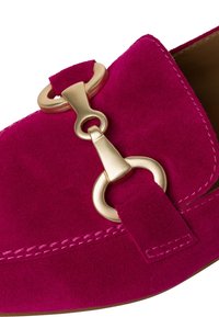 Fuchsiové semišové mokasíny s zlatým kovovým akcentem a prošívaným detailem podél okraje. Plochá podešev a kulatý tvar špičky.
