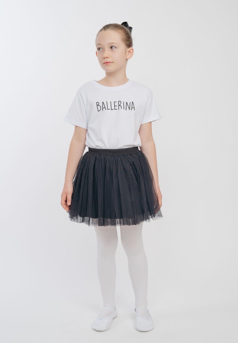 Weißes T-Shirt mit dem Aufdruck "BALLERINA", kombiniert mit einem schwarzen Tüllrock, weißen Strumpfhosen und weißen Ballettschuhen. Einfaches Design, weiche Texturen.