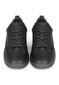 Zapatillas negras con parte superior de cuero texturizado, puntera redonda, cordones planos y suela de goma. Diseñadas para uso casual. Sin patrones ni acentos visibles.