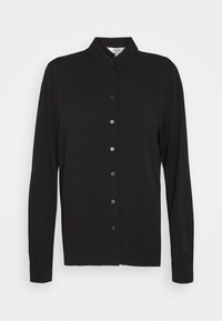 Chemise noire à manches longues en tissu lisse avec un devant à boutons, un col et des poignets droits. Elle comporte sept boutons sur le devant.