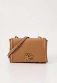 Καφέ δερμάτινη τσάντα με δομημένο σχήμα, εξαρτήματα σε χρυσό τόνο, λουρί ώμου και ανάγλυφο λογότυπο στο μπροστινό μέρος.