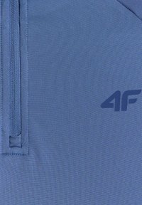 Tissu bleu texturé avec un détail de fermeture éclair verticale à gauche et un logo "4F" bleu foncé sur le côté droit.