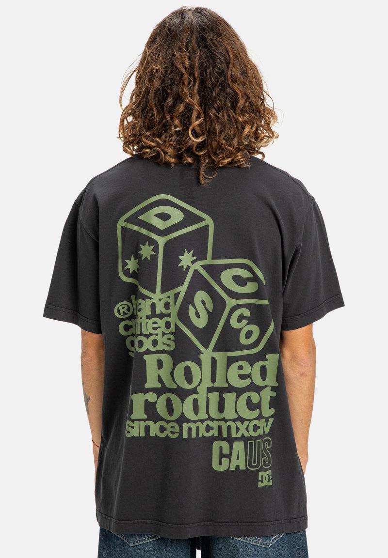 Sort oversized T-shirt med grøn grafisk design, der indeholder terninger, textelementer og brandlogo. Blødt bomuldsstof med afslappet pasform.