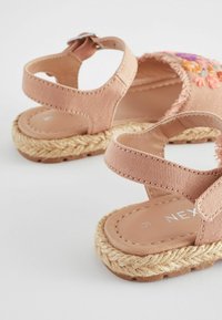Rosa Stoffsandalen mit zwei verstellbaren Riemen, geflochtener Jutesohle und Blumenstickereien im oberen Bereich.