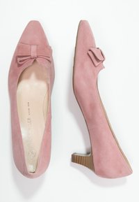Decolletè in camoscio rosa con punta affusolata e dettaglio a fiocco. Tacco basso in legno, interno liscio e suola testurizzata. Design con suola piatta per maggiore stabilità.