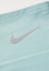 Svijetloplavo atletsko platno s srebrnim Nike logotipom. Glatka tekstura s ravnim šavom blizu gornjeg ruba.
