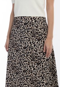 Mønstret midi-nederdel i leopardprint i beige og brun, med en blød tekstur og flydende design. Elastisk talje, med hænder der let berører stoffet.