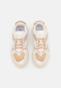 Sneakers Lacoste in beige chiaro, con texture in rete e camoscio, accenti bianchi, lacci pastello e suola in gomma con dettagli del logo.