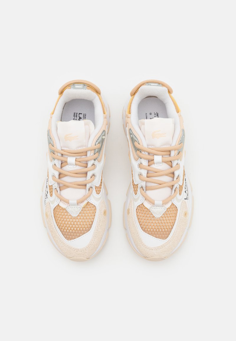 Zapatillas Lacoste en un suave beige, con texturas de malla y gamuza, detalles en blanco, cordones en tonos pastel y una suela de goma con detalles del logo.