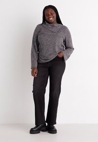 Haut à manches longues gris côtelé avec un col drapé, associé à un pantalon noir à jambes droites et des chaussures à plateforme noires. Design simple, tissu texturé.