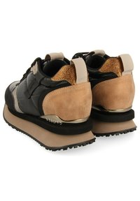 Baskets noires et beiges avec un dessus rembourré, des détails en daim, des accents métalliques et une semelle en caoutchouc noir texturée.