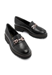 Czarne skórzane mokasyny o teksturowanym wykończeniu, z szerokim paskiem i różowym złotem metalowym akcentem. Grube podeszwy zapewniają dodatkowe wsparcie.