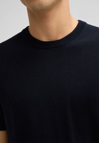 Marineblaues Strick-T-Shirt mit rundem Halsausschnitt und kurzen Ärmeln. Der Stoff wirkt weich mit einer glatten Textur und hat eine enganliegende Passform.