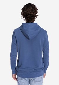 Blauer Hoodie aus weichem Stoff mit Kordelzugkapuze, langen Ärmeln und lockerer Passform. Die Rückseite zeigt eine einfache, glatte Textur.