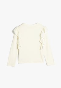 Pitkähihaiseen paita off-white ribbed-materiaalista, jossa on koristeelliset rypyttämät molemmilla harteilla ja klassinen pyöreä pääntie.