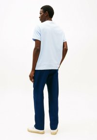 Camiseta de manga corta azul claro con escote redondo, combinada con pantalones azul oscuro. El conjunto incluye zapatillas blancas y tiene una textura suave.