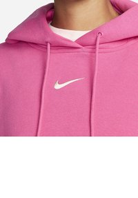 Pink hoodie made of soft cotton blend with a kangaroo pocket. Features a small white Nike logo on the chest and drawstrings at the hood.